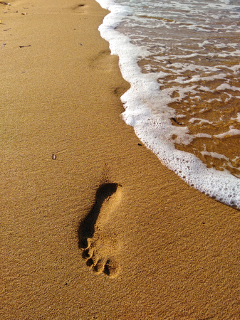 Lonely footprint at the beach. Trace at sand and sea wave. Peaceful lonely mood. Psychology or phylosophy symbol.の写真素材