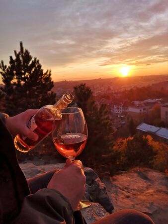 Pouring wine into wineglass at the sunsetの写真素材