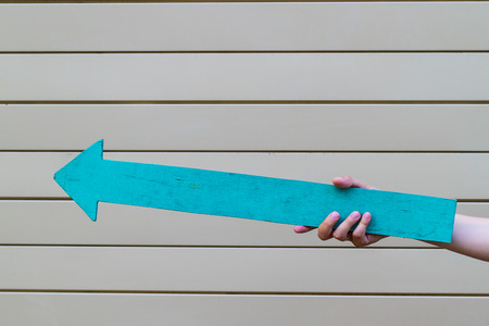 Hand holding a blue arrow pointed up and leftの写真素材