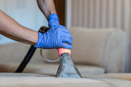 Closeup of upholstered Sofa chemical cleaning with professionally extraction method. Man is holding nozzle.の写真素材