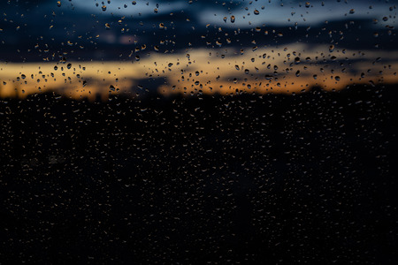 Closeup of raindrops on window in the evening, beautiful sunset colors