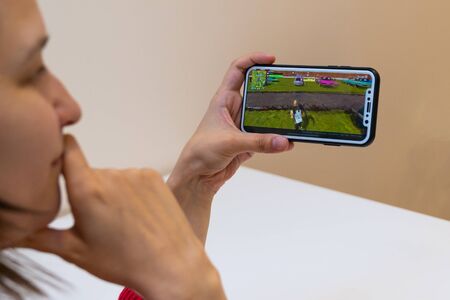 Elva, Estonia - November 15, 2018: girl is holding iphone with online Fortnite game on display,...