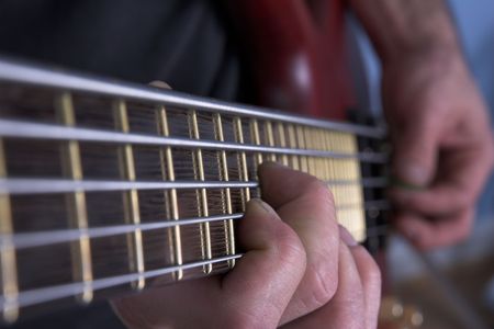Closeup of five string bass guitar being played
