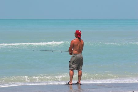 Young man fishing in florida on ocean beach on day offの写真素材