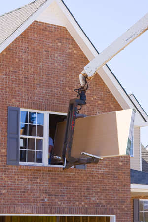 Truck driver delivering sheet rock to second floor of new home