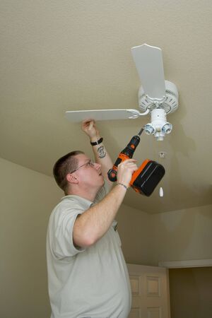 Electrician installing new light fixture and fan combinationの写真素材