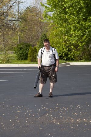 Maintenance man cleaning parking lot at apartment complex