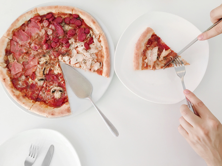 Pizza with red tomatoes, mozzarella cheese on top of a white table