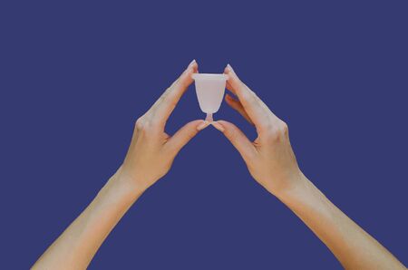 Menstrual cup in hands on blue background. Alternative feminine hygiene productの写真素材