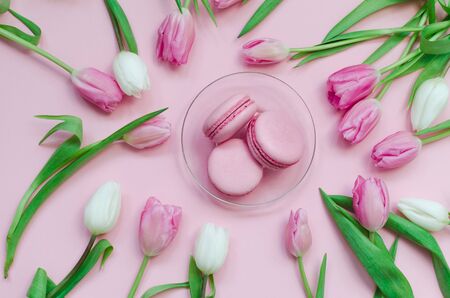 Pink fresh macarons with tulips around on pink background, top view. Greeting for Mothers Dayの写真素材
