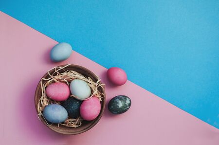Bright easter greeting background with dyed multicolored chicken quail eggs on straw in plate