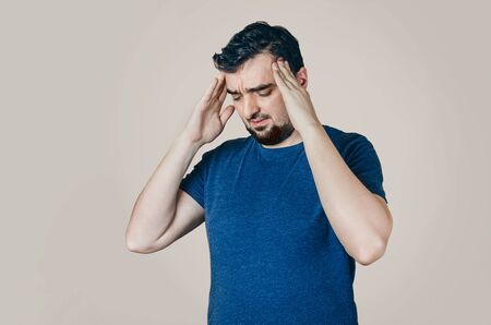 Men in the t-shirt holding hands to his head. Health problems. suffering from problems at home or at...