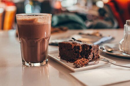 Homemade chocolate brownie with nuts on plate with hot chocolate close up on wooden tableの写真素材