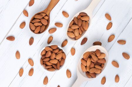 Flatlay view of almond milk in glass with almond seeds and wooden spoons on white wooden table plateの写真素材