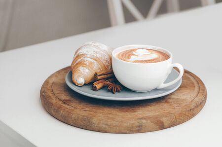 Fresh baked croissant with coffee cup and latte art, cinnamon and star aniseの写真素材