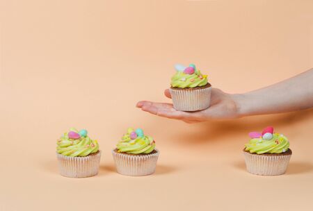 Row of bright pistachio Easter cupcake with decorations in hand close up
