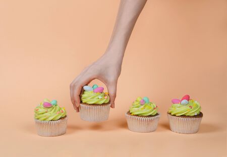 Row of bright pistachio Easter cupcake with decorations in hand close upの写真素材
