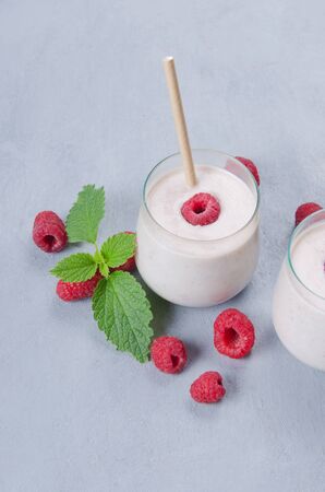 Glass of raspberry milkshake with mint on wooden backgroundの写真素材