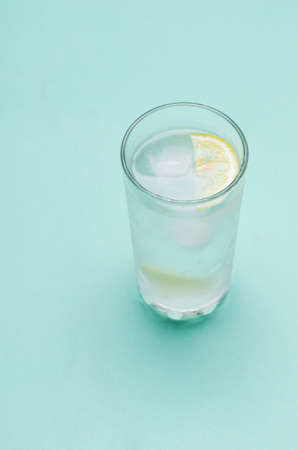 Cocktail with ice and lemon slice on bright blue backgroundの写真素材