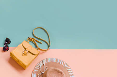 Beautiful summer straw with sunglasses and orange bag on pastel color