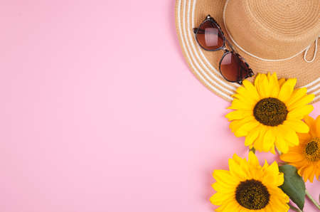 Flatlay with sunglasses, straw hat and bright yellow sunflower on pink backgroundの写真素材