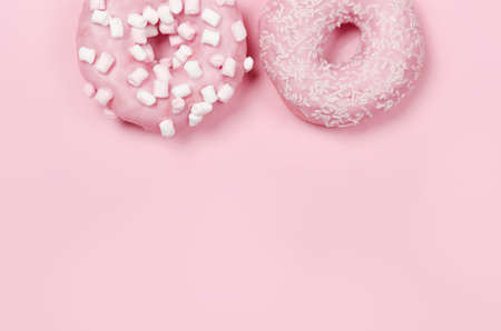 Two donuts with icing on pastel pink background. Sweet donuts. Copyspaceの写真素材