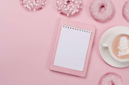 Notepad wish list for future plans. flat lay composition with donuts, notepad and cup of coffee on pink backgroundの写真素材
