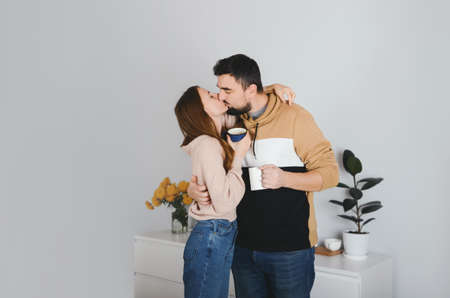 Lovely cheerful young couple man and woman kissing at homeの写真素材