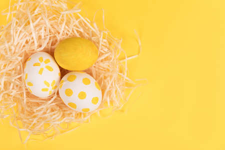 Nest with painted color easter eggs on yellow backgroundの写真素材