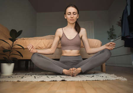 Young woman in the lotus position meditating at home.