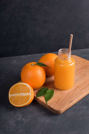 Glass of fresh orange and mango juice and slice of orange fruit on dark backgroundの写真素材