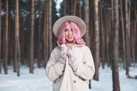 Pink hair woman looking happy outdoors in snow on cold winter day.