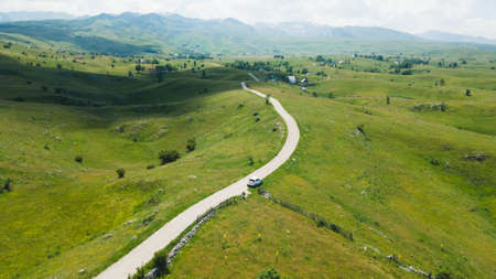 Aerial footage a car driving over beautiful green mountain road in Pisce, Montenegro. air view