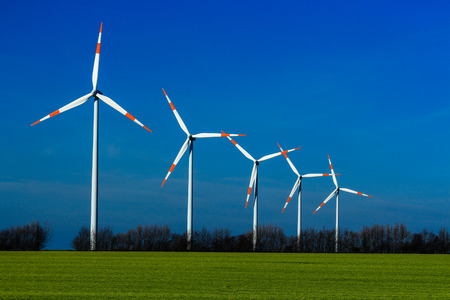 windmills at work with a green field and dark blue sky representing clean source of energy
