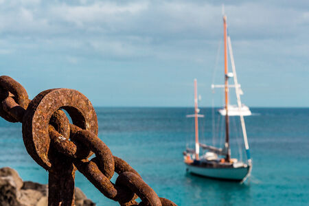 Sailing boat at anchor with massive metal chain representing a safe havenの写真素材