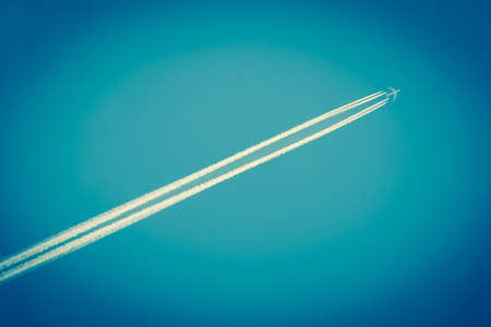 Airplane with diagonal trails of fumes in a dark blue skyの写真素材