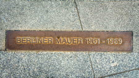 remembering the Berlin Wall - iron plate to remember the Berlin Wall in the pavement of a Berlin Streetのeditorial素材