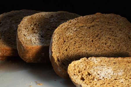 Several slices of rye bread covered with mold are located on the table one after another. Photo at...