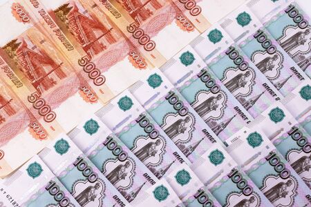 Russian banknotes of a thousand, five thousand rubles in two rows lie on a table with a white background.の写真素材