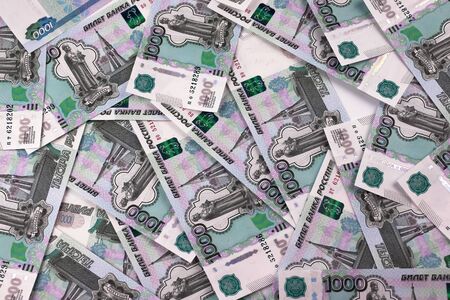 Russian banknotes in denominations of a thousand rubles are scattered on a white table in disarray.の写真素材