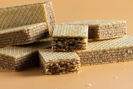 A few pieces of crispy wafers with brown filling lie on a table with a beige background.の写真素材