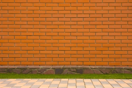 Brick wall with a stone border and green grassの写真素材