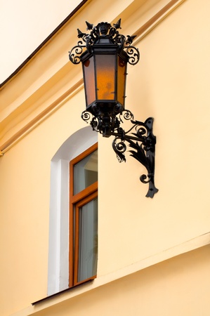 Fragment of the wall with the window and the old iron street lampの写真素材