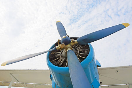 The engine and propeller plane close-up on a background of blue sky and clouds. The picture at the low point.の写真素材
