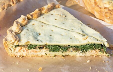 Slice of homemade pie with salmon and spinach. Picture taken at the spring fair under the open sky on a sunny day. Close-up.の写真素材