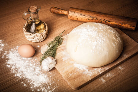 dough on a board with flour. olive oil, eggs, rolling pin, garlicの写真素材