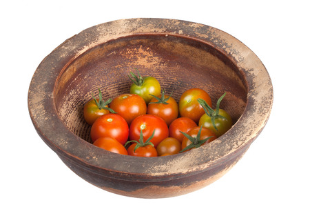 freshly picked tomatoes in a wooden old plate isolated on white backgroundの写真素材