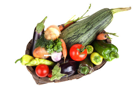 assorted vegetables in an old wooden basket isolated on white backgroundの写真素材