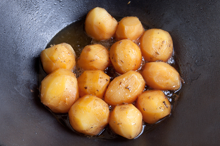 whole fried potatoes in oil in a cauldronの写真素材
