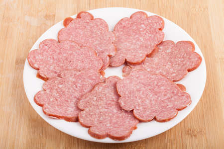 sliced ââsausage on a white plate on woodの写真素材